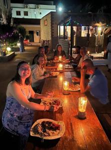 um grupo de pessoas sentadas à volta de uma mesa a comer pizza em Oasis Fighting Kangaroo em Dahab