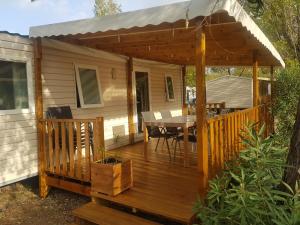 une terrasse en bois avec une table sur une maison dans l'établissement Mobil Home 6 à 8 personnes Camping Vagues Océanes L'Elysée, au Grau-du-Roi