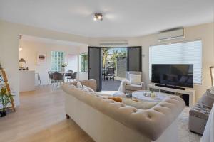 a living room with a couch and a tv at Elegant 2BR Family Home - Aircon - 5min to Beach in Auckland