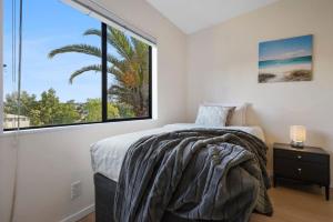 a bedroom with a bed and a large window at Elegant 2BR Family Home - Aircon - 5min to Beach in Auckland