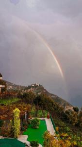 een regenboog boven een tuin met een groen gazon bij Residence Eden in Furore