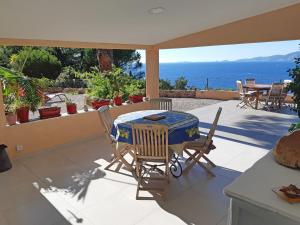 une terrasse avec une table et des chaises et l'océan dans l'établissement Les Terrasses du Pano - 76 m2 au calme - Jardin - Barbecue - Transats - Pleine vue mer - Wifi Fibre, à Porticcio