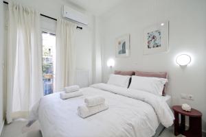 a white bedroom with a large bed with towels on it at Athens Delight Apartment in Pagrati in Athens