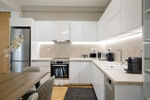 a kitchen with white cabinets and a wooden table at Athens Delight Apartment in Pagrati in Athens