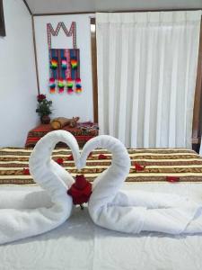 two swans made to look like hearts sitting on a bed at Q'OTA TAYPY LODGE in Puno