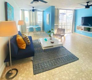KASA Royal Palms في سان خوان: غرفة معيشة مع أريكة زرقاء وطاولة
