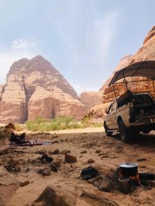 een auto geparkeerd in de woestijn met bergen op de achtergrond bij desert splendor camp & jeep tours in Wadi Rum