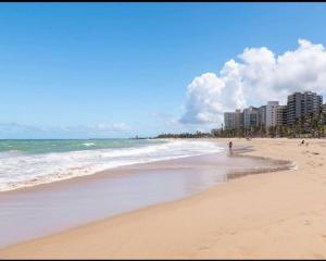 a person walking on a beach near the ocean at KASA Royal Palms in San Juan