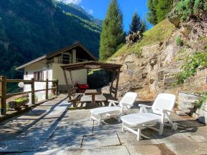 eine Terrasse mit weißen Stühlen und einem hölzernen Unterstand in der Unterkunft Casa Schiappo Montagna Natura e Relax. in Iselle