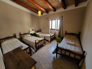 a room with four beds and a table and a window at HOSPEDAJE LA CASONA DE CACHI in Cachí