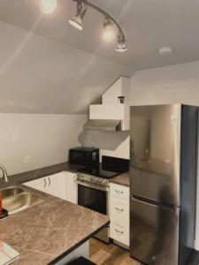kuchnia z lodówką ze stali nierdzewnej i białymi szafkami w obiekcie Rustic 1-Bedroom farm style loft with fire pit w mieście Cobble Hill
