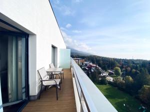 a balcony with two chairs and a table on it at Apartman Deluxe Štrbské Pleso in Štrbské Pleso