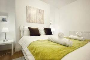 a white bedroom with a large bed with towels on it at Urban Music Style Townhouse in Swansea city center in Swansea