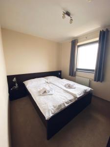 una camera da letto con un letto con lenzuola bianche e una finestra di Apartman Deluxe Štrbské Pleso a Štrbské Pleso