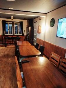 Madarao Mountain Lodge في Iiyama: مطعم بطاولات وكراسي خشبية وتلفزيون بشاشة مسطحة