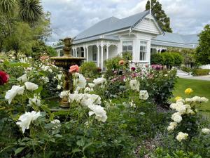 a white house with a garden of flowers at Villa Walton Bed & Breakfast in Matamata
