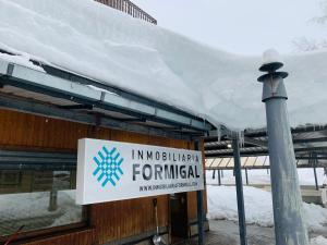 ein Schild auf einem Gebäude mit Schnee auf dem Dach in der Unterkunft Apartamentos Formigal - admite mascotas in Formigal