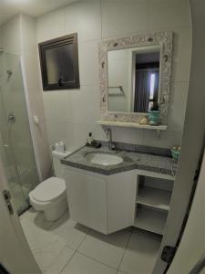 een badkamer met een wastafel, een toilet en een spiegel bij VG Sun Cumbuco Sea Breeze Vista Mar in Cumbuco