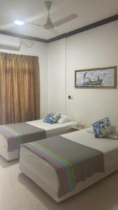 a bedroom with two beds and a painting on the wall at Coco Cottage Local Style in Guraidhoo