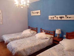 a bedroom with two beds and a blue wall at Casa Los Lagares in Peral de Arlanza