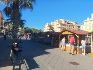 a group of people sitting on a bench at an outdoor market at Appartamento centrale in Lido di Ostia