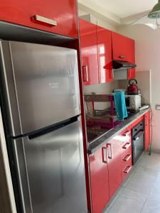 a kitchen with red cabinets and a stainless steel refrigerator at Mohammédia Marbella beach appartement familliale in Mansouria