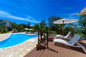 a deck with chairs and an umbrella next to a pool at Best Western Okinawa Onna Beach in Onna