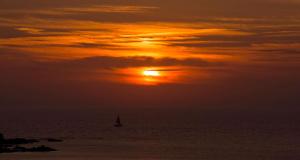 een zonsondergang boven de oceaan met een zeilboot bij Best Western Okinawa Kouki Beach in Nago