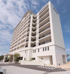 a large white building with a car parked in front of it at Best Western Okinawa Kouki Beach in Nago