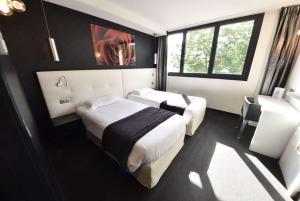 a hotel room with two beds and a window at Hotel Le Quercy - Sure Hotel Collection by Best Western in Brive-la-Gaillarde