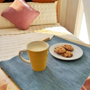 a cup and a plate of cookies on a bed at Departamento para 6 personas a 3 minutos del aeropuerto in Cusco