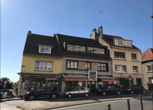 un grand bâtiment avec des voitures garées devant lui dans l'établissement La Maison Du Bois Flotté, à Boulogne-sur-Mer