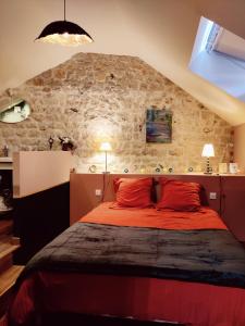 a bedroom with a red bed with a stone wall at La Mansarde in Vernon
