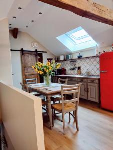 una cucina con tavolo, sedie e frigorifero rosso di La Mansarde a Vernon