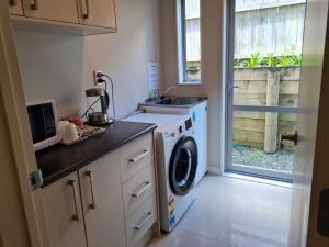 a kitchen with a washing machine and a sink at Sweet home in Albany in Auckland
