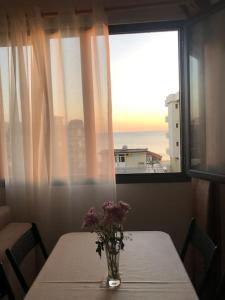 a table with a vase of flowers on it with a window at Sea View Deluxe Apartment in Durrës