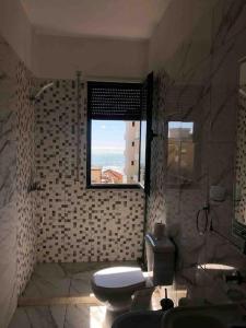 a bathroom with a toilet and a window at Sea View Deluxe Apartment in Durrës