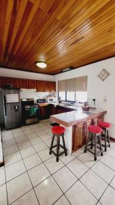 a kitchen with a counter and two red bar stools at Don Carlos Place in Alajuela City