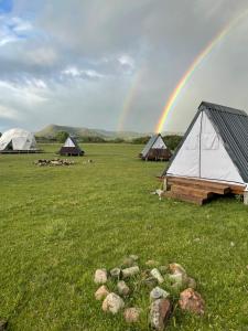 a rainbow over a field with tents and rocks at Villa Pancha del Lunarejo in Sierra de Lunarejo