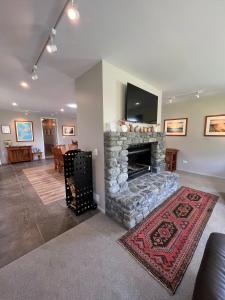 a living room with a stone fireplace with a flat screen tv at Manakau Lodge in Kaikoura