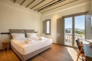 a white bedroom with a bed and a balcony at Fabrikas in Mikonos