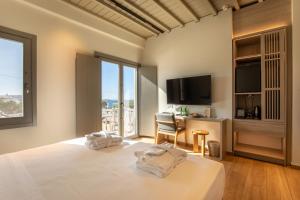 a bedroom with a bed with a television and a desk at Fabrikas in Mýkonos City