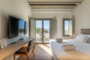 a bedroom with a bed and a desk with a flat screen tv at Fabrikas in Mýkonos City +165 photos