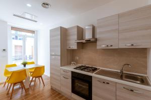 una cocina con armarios de madera y una mesa con sillas amarillas. en Central House - Apartments in Naples, en Nápoles