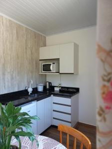 a kitchen with white cabinets and a microwave at Hospedaria Mitterer in Treze Tílias +8 photos