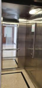 a metal elevator with a glass door in a room at Hotel Fatti in Maringá