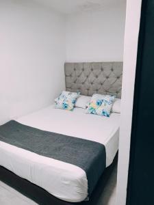 Una gran cama blanca con almohadas azules. en Hotel Tranvia, en Santa Marta