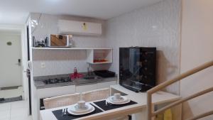 Una pequeña cocina con una mesa y un microondas. en Laguna Beach Flat, en Porto de Galinhas