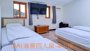 a bedroom with two beds and a flat screen tv at 芹壁幸福海岸民宿-民宿編號051 in Beigan
