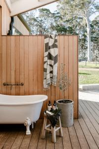 a bath tub sitting on a deck next to a wooden fence at Upland Farm Luxury Cabins, Denmark Western Australia in Denmark
